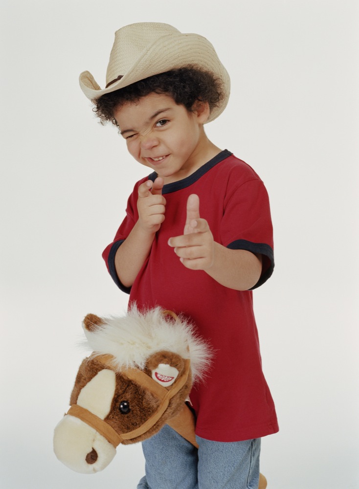 Boy (4-6) riding hobby horse, pretending to shoot, portrait