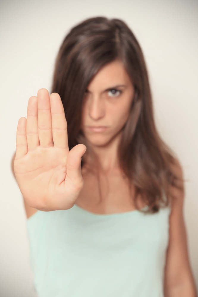 A girl in mint top with a stop gesture looking at the camera