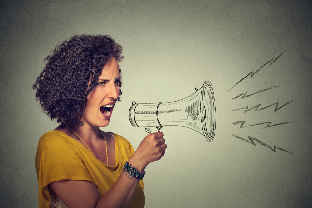 angry screaming young woman holding megaphone